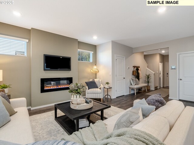 living area with wood finished floors, a glass covered fireplace, plenty of natural light, and recessed lighting