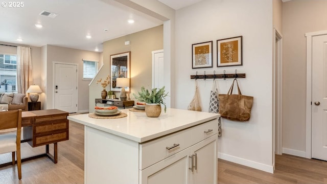 kitchen with visible vents, light wood-style floors, open floor plan, white cabinetry, and baseboards