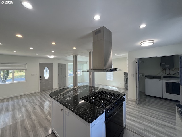 3345 SW 124th Ave, Beaverton, OR 97005 - kitchen with island exhaust hood, black gas stove, decorative columns, washer and dryer, and recessed lighting