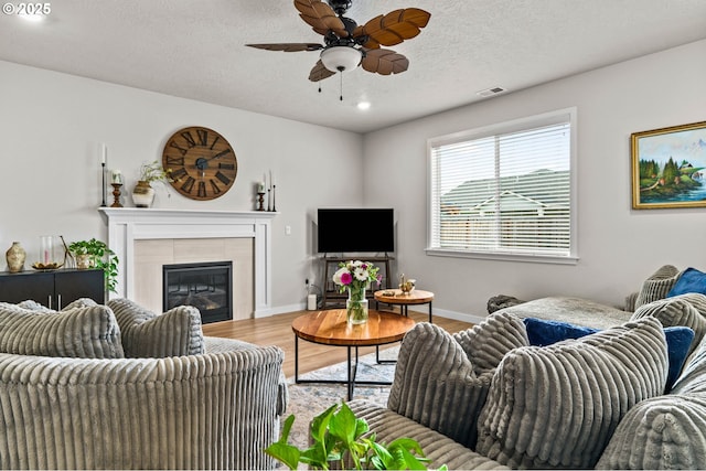 living area featuring wood finished floors, a ceiling fan, a fireplace, recessed lighting, and baseboards