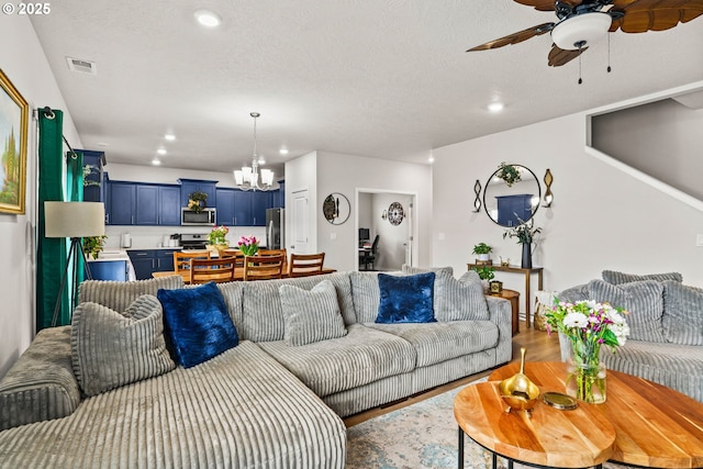 living room featuring a chandelier, a ceiling fan, recessed lighting, wood finished floors, and a textured ceiling
