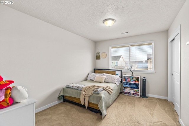 bedroom with carpet floors, baseboards, a textured ceiling, and a closet