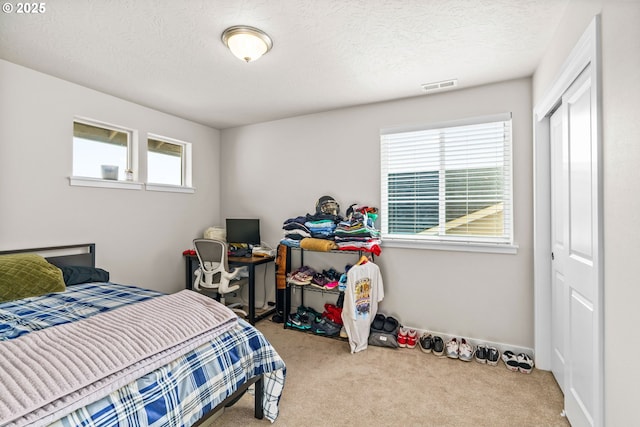 carpeted bedroom featuring a closet, a textured ceiling, and baseboards