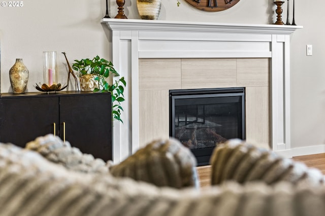 detailed view of a tiled fireplace, wood finished floors, and baseboards
