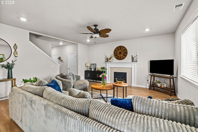 living area with wood finished floors, ceiling fan, recessed lighting, a glass covered fireplace, and baseboards