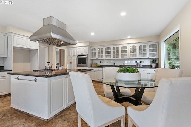 3025 SW Wallula Ave, Gresham, OR 97080 - kitchen with island range hood, decorative backsplash, dark countertops, glass insert cabinets, and recessed lighting