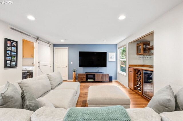 13355 SW Chimney Ridge Ct, Tigard, OR 97223 - living area with beverage cooler, a barn door, a bar, light wood-style flooring, and washer / dryer