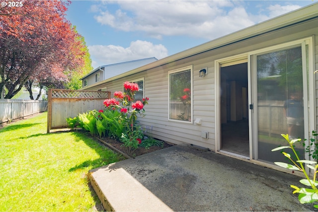 doorway to property with fence, a lawn, and a patio