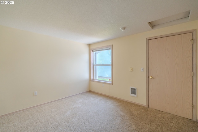 carpeted empty room with attic access, heating unit, and baseboards
