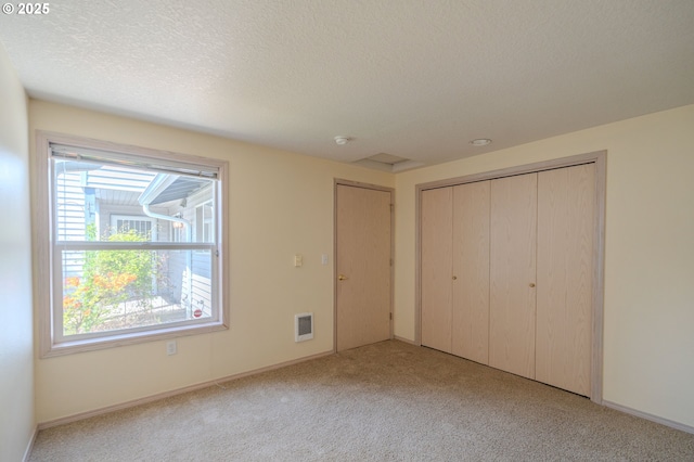 unfurnished bedroom featuring multiple windows, carpet, and visible vents