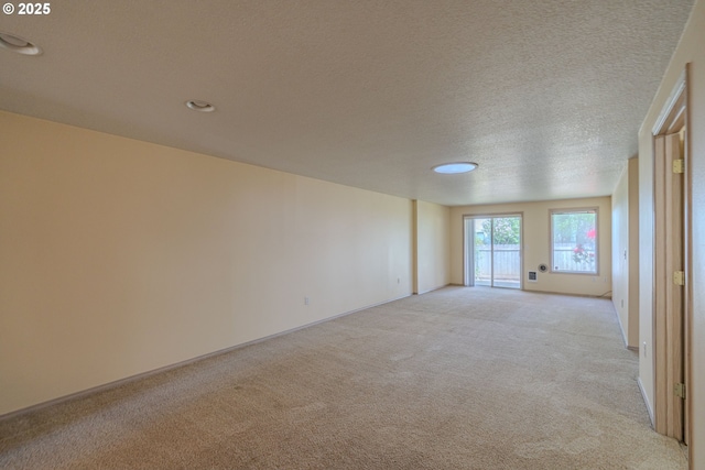 empty room with recessed lighting, a textured ceiling, light carpet, and baseboards