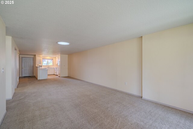 interior space featuring a textured ceiling, light carpet, and baseboards
