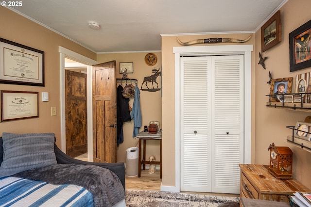 bedroom with a closet, wood finished floors, and crown molding