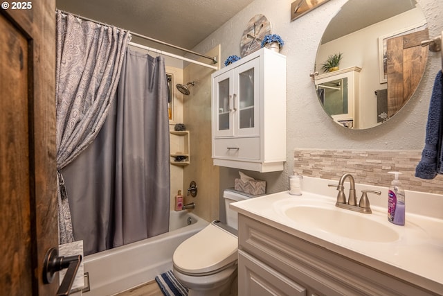 bathroom with shower / bath combination with curtain, a textured wall, toilet, vanity, and a textured ceiling