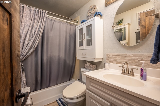 bathroom with toilet, vanity, shower / tub combo with curtain, and a textured wall