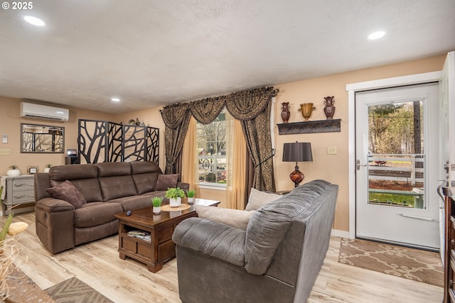 living room with light wood-style floors, recessed lighting, an AC wall unit, and a textured ceiling