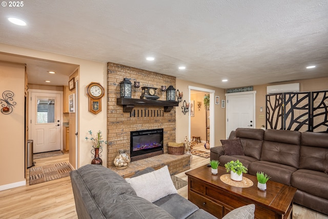 living area featuring a textured ceiling, recessed lighting, a fireplace, light wood finished floors, and a wall mounted air conditioner