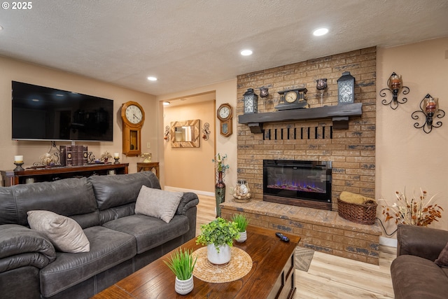 living area featuring a textured ceiling, a brick fireplace, wood finished floors, and recessed lighting