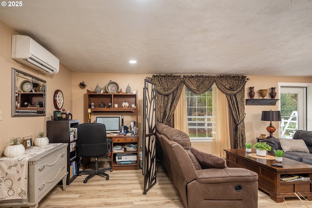 office area with light wood-style flooring, a textured ceiling, and a wall mounted AC