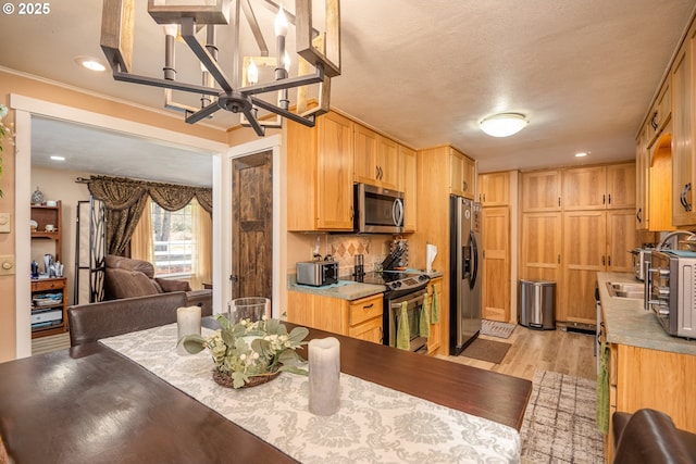 kitchen with recessed lighting, an inviting chandelier, appliances with stainless steel finishes, light wood-style floors, and open floor plan