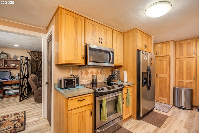 kitchen with stainless steel appliances, light brown cabinetry, light wood-style floors, and tasteful backsplash