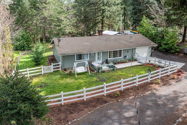 single story home with a shingled roof, concrete driveway, an attached garage, fence private yard, and a front lawn