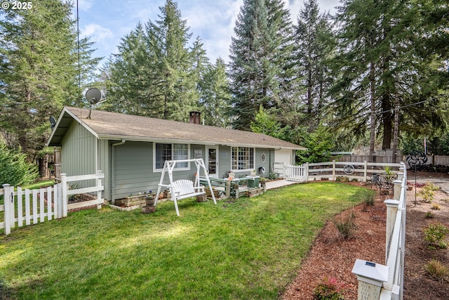 back of house featuring a yard, a chimney, and fence