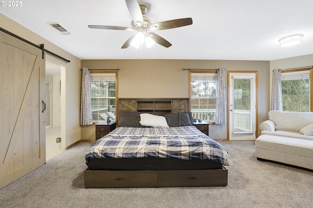 carpeted bedroom featuring a barn door and ceiling fan