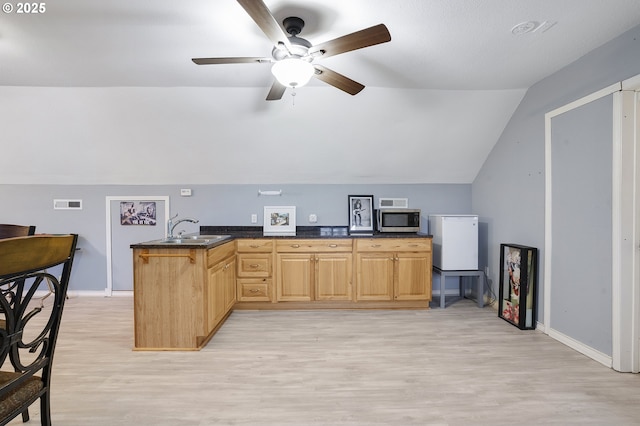 kitchen with light wood-type flooring, sink, light brown cabinetry, and kitchen peninsula