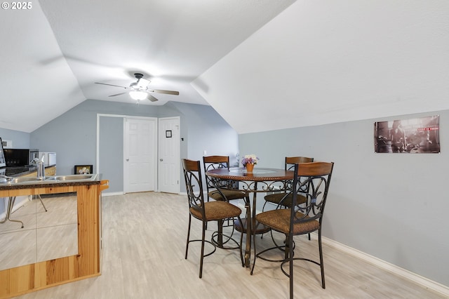 dining space with sink, hardwood / wood-style flooring, vaulted ceiling, and ceiling fan