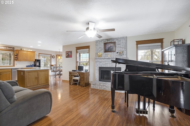 interior space featuring a textured ceiling, a fireplace, ceiling fan, and light wood-type flooring