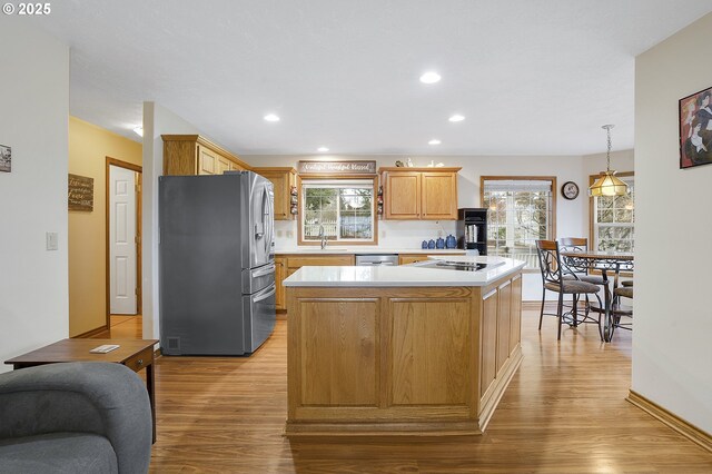 kitchen featuring appliances with stainless steel finishes, a wealth of natural light, hanging light fixtures, a center island, and light hardwood / wood-style flooring