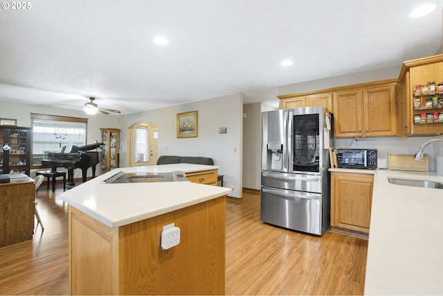 kitchen with sink, light hardwood / wood-style flooring, stainless steel fridge, ceiling fan, and a kitchen island