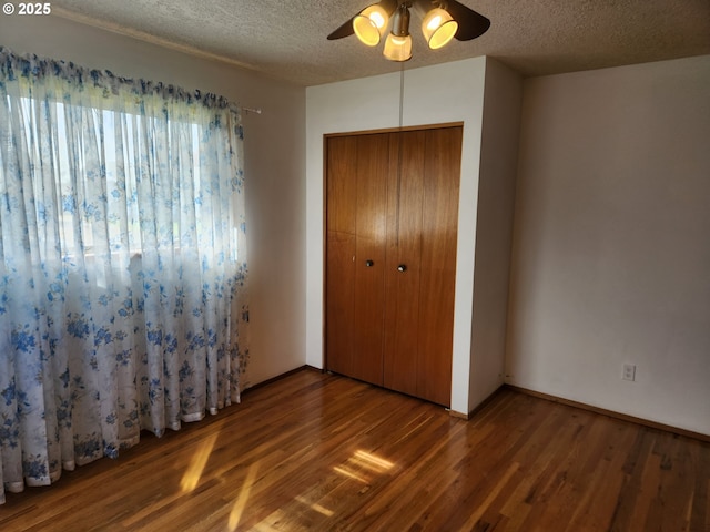 unfurnished bedroom featuring a closet, a ceiling fan, wood finished floors, and a textured ceiling