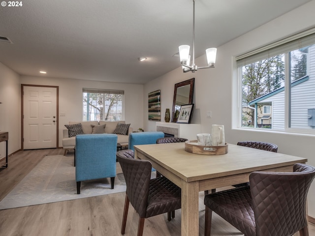 dining space featuring an inviting chandelier, a wealth of natural light, and light hardwood / wood-style flooring