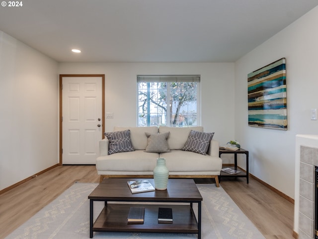 living room featuring a tile fireplace and light wood-type flooring