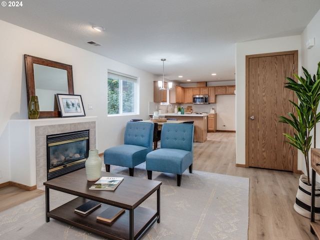 living room with a tile fireplace, sink, and light hardwood / wood-style flooring