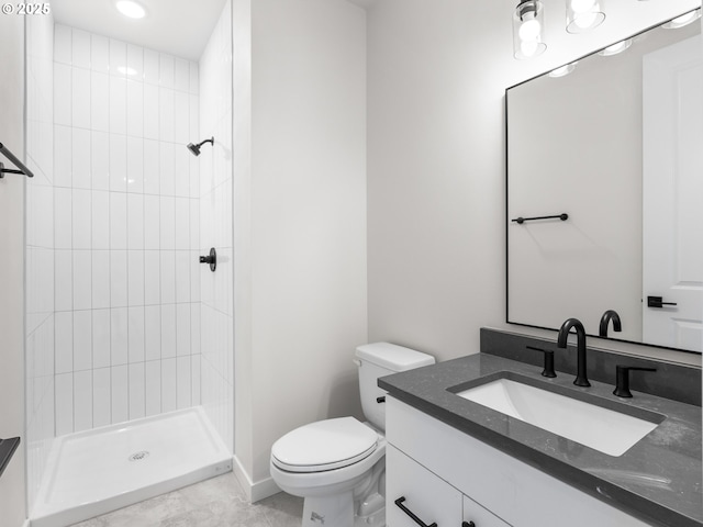 bathroom with a tile shower, vanity, and toilet