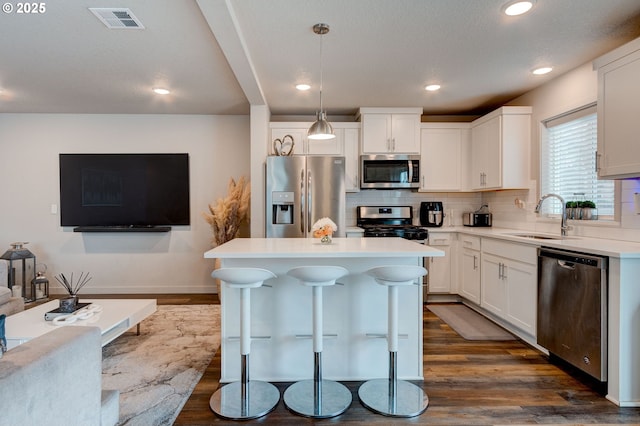 9911 SE Duke St, Portland, OR 97266 - kitchen with stainless steel appliances, visible vents, decorative backsplash, dark wood-type flooring, and a sink