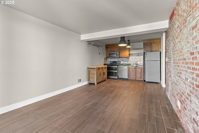 kitchen with backsplash, dark wood-type flooring, stainless steel appliances, and brick wall