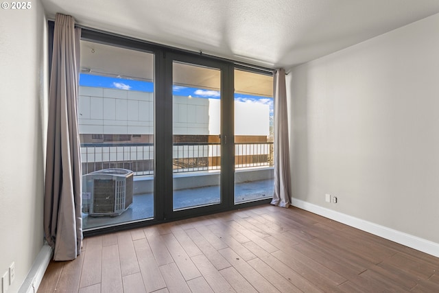 unfurnished room with hardwood / wood-style floors, expansive windows, and a textured ceiling