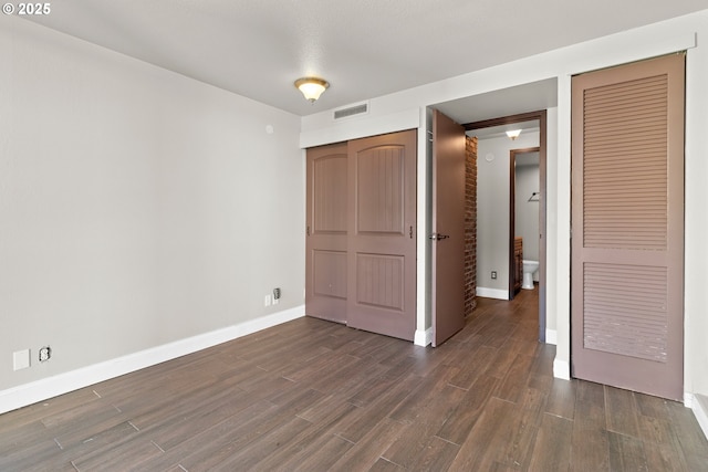 unfurnished bedroom with dark hardwood / wood-style flooring and a closet