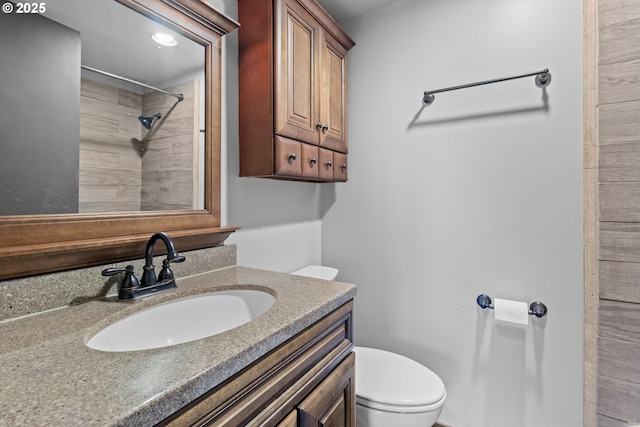 bathroom featuring vanity, toilet, and a tile shower