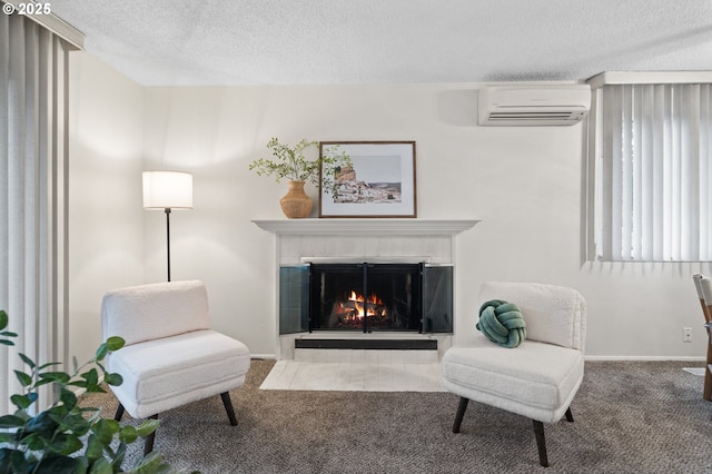 living area featuring baseboards, a wall unit AC, a textured ceiling, carpet flooring, and a fireplace