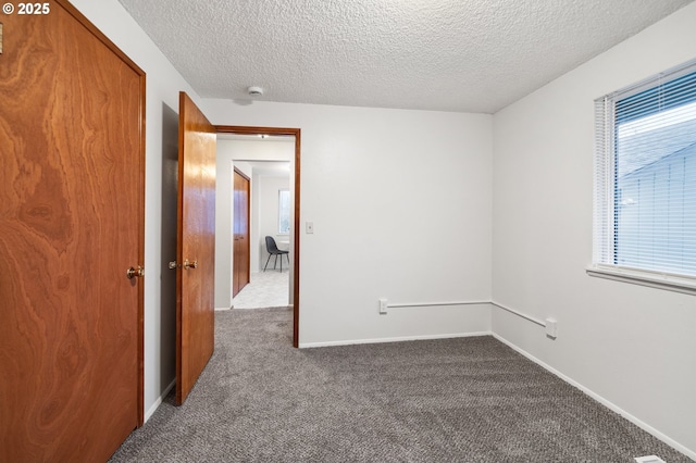 carpeted spare room with a textured ceiling and baseboards