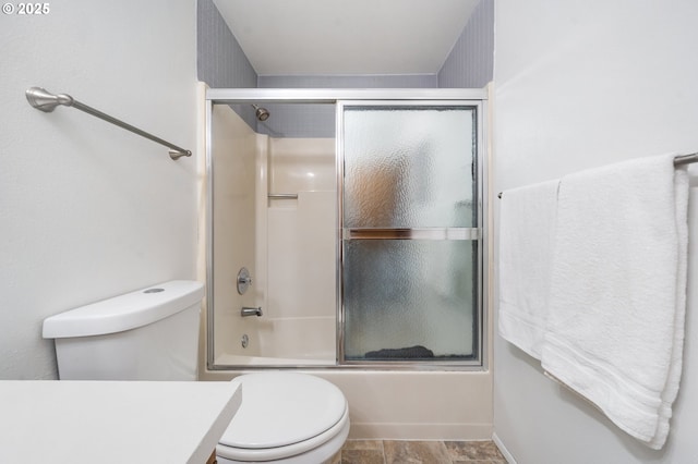 full bath featuring toilet and shower / bath combination with glass door