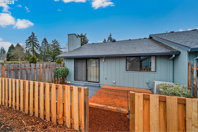 view of front of house featuring roof with shingles, fence, and a chimney