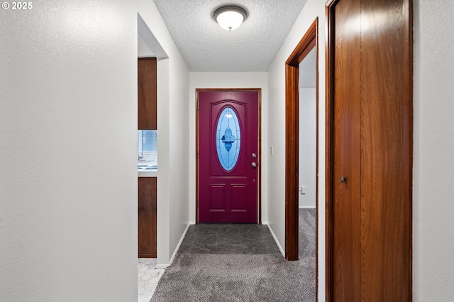 doorway with carpet, baseboards, and a textured ceiling