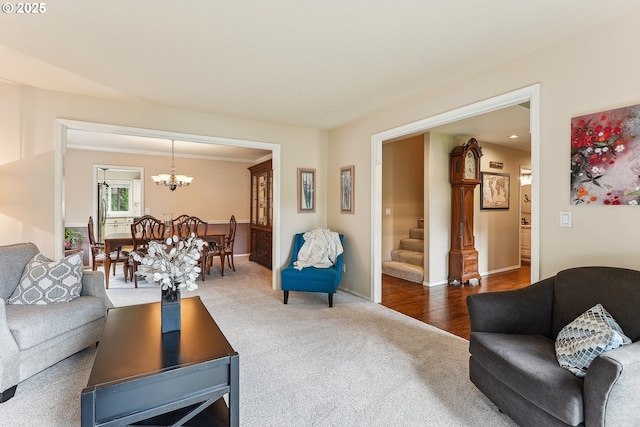 carpeted living room featuring an inviting chandelier, baseboards, and stairs