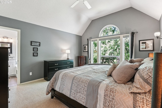 bedroom with a ceiling fan, vaulted ceiling, connected bathroom, and light colored carpet